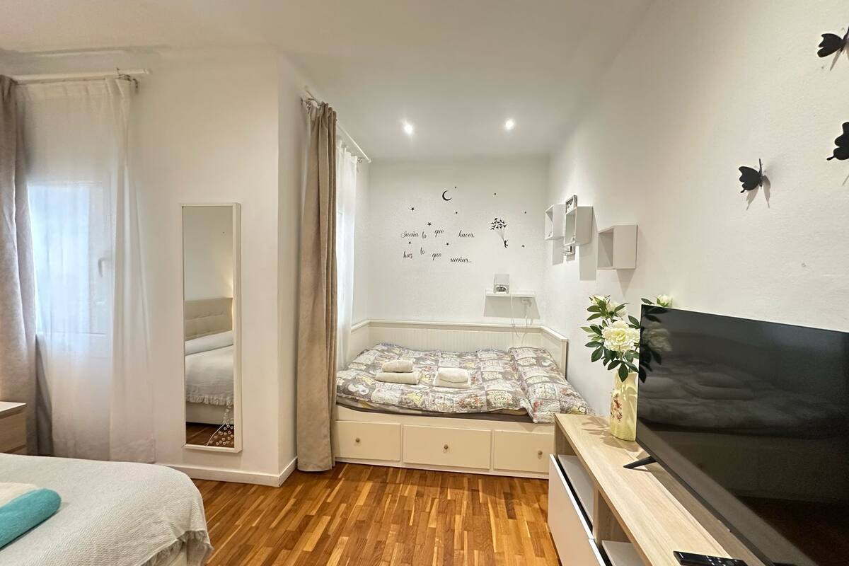 Une chambre à coucher comprenant un lit, une télévision, un miroir et un mur agrémenté d’éléments décoratifs.