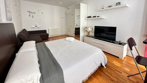 Une chambre moderne avec un grand lit, une télévision, un bureau et une chaise.