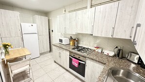Une cuisine moderne avec des meubles blancs, une cuisinière à gaz, un four à micro-ondes et un évier.