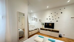 Une chambre moderne avec un grand lit, une télévision et un mur décoré d’autocollants représentant des papillons.