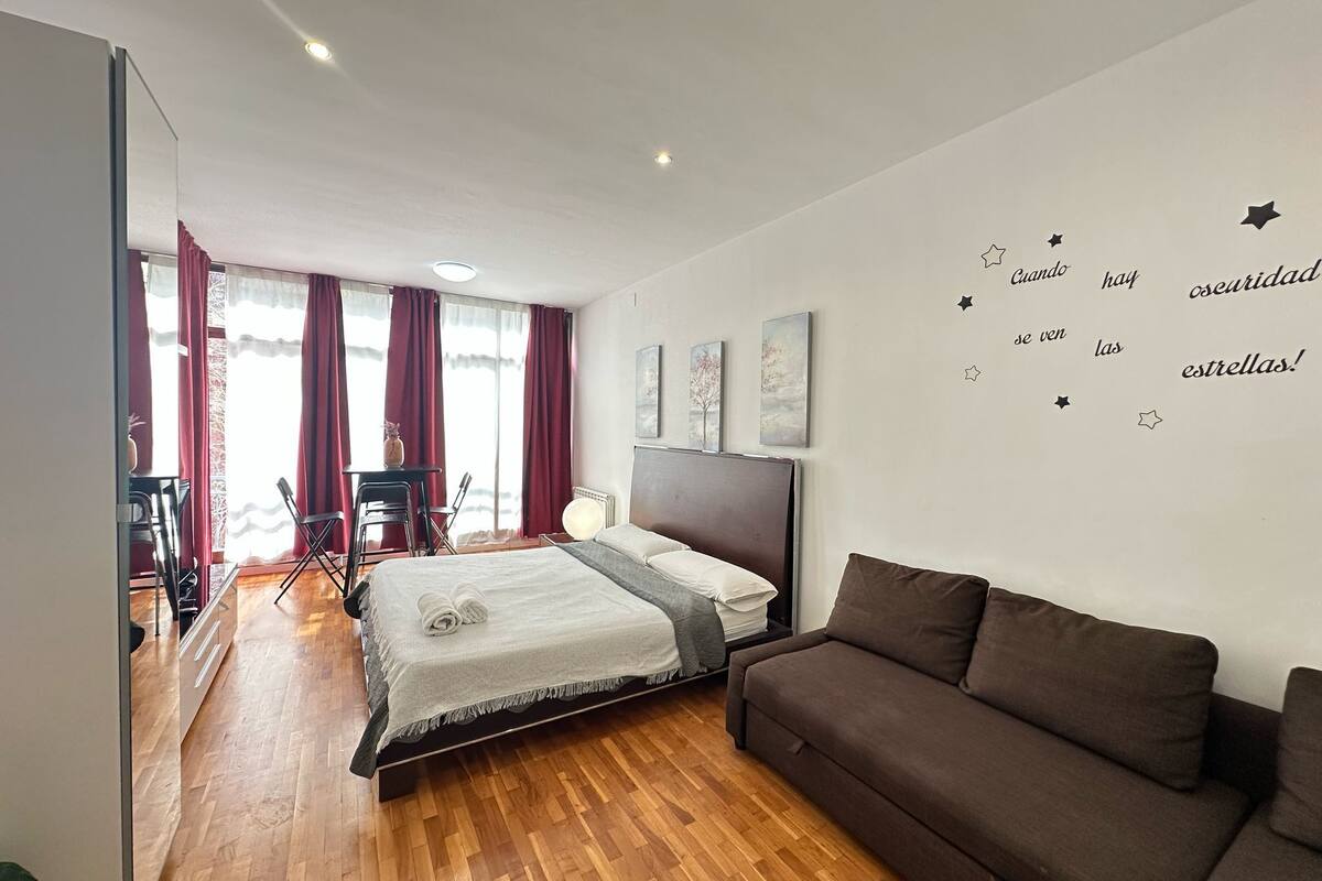 Une chambre moderne avec un grand lit, un canapé marron et un bureau avec des chaises.