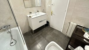 Une salle de bain moderne avec une baignoire, un lavabo avec un miroir et des toilettes.