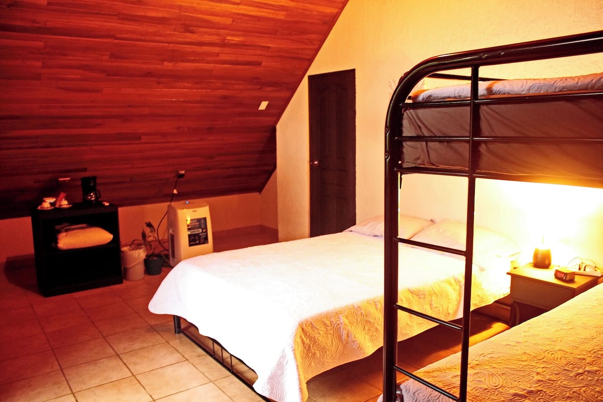 A single bed with a metal frame in a room with wooden ceiling and walls.