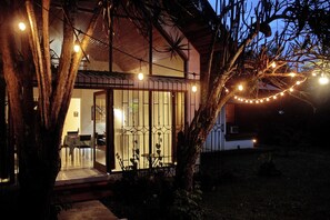 Ein Haus mit Glastür, einem Essbereich inklusive Stühle und Tisch sowie Lichterketten.