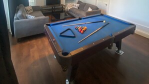 Een woonkamer met een pooltafel, een bank en een kroonluchter.