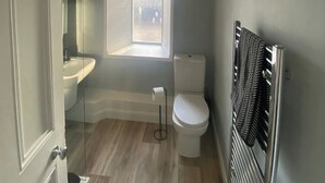 Een badkamer met een raam, toilet, wastafel en handdoekhouder.
