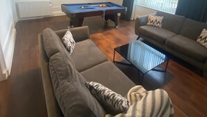 Een woonkamer met een pooltafel, een bank en een salontafel.