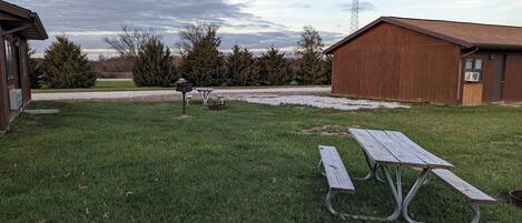 Un espacio al aire libre con césped, mesas de picnic y un cobertizo.