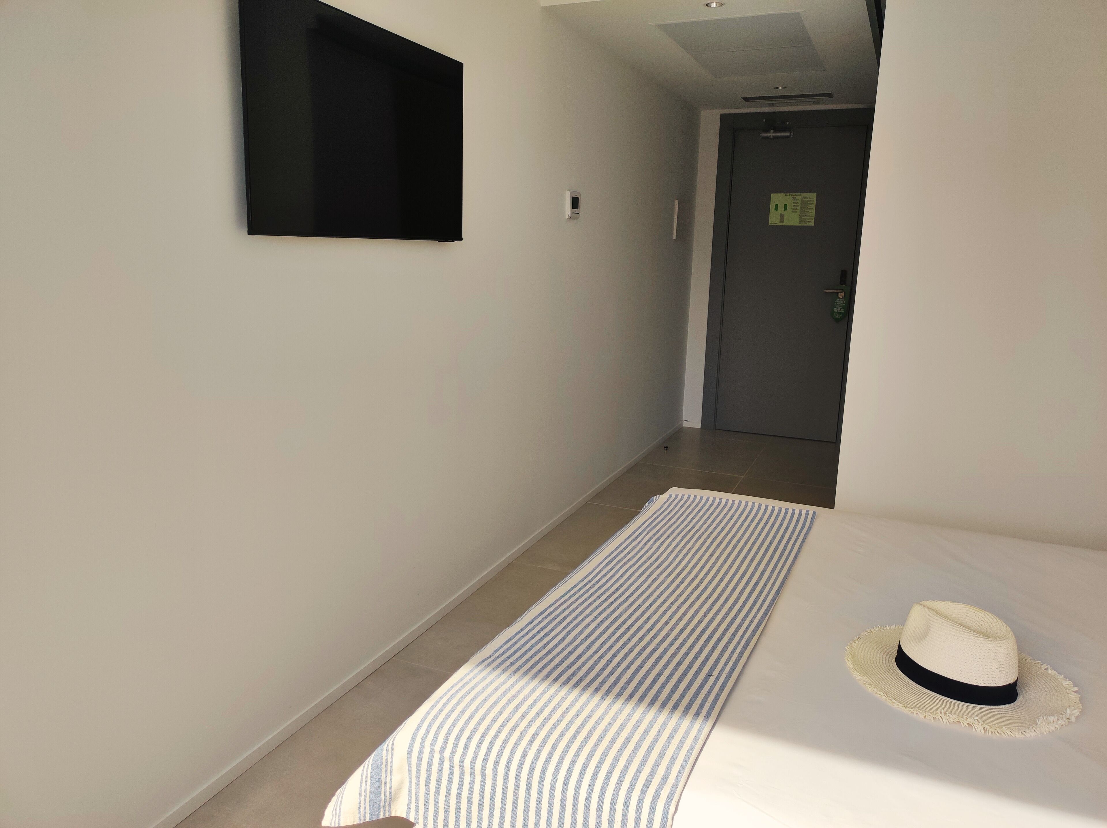 A hotel room with a bed, a hat, and a door in the background.