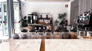 Mostrador de cafetería con diversos granos de café y especias exhibidos en frascos.