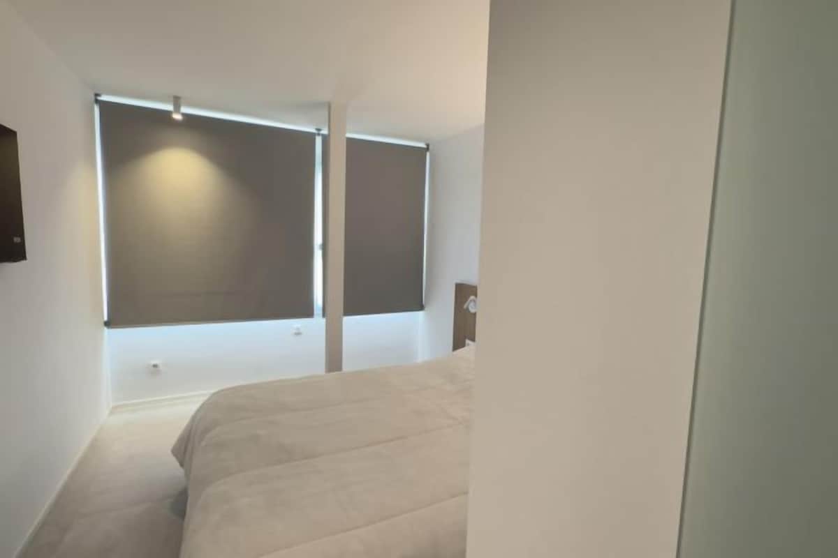 A bedroom with a bed, a window, and a door.