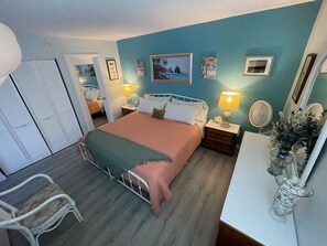 A bedroom with a bed, bedside tables, a chair, and a mirror. - Sunset & Ocean Front Views-FM-Beach(Pool is Open) (Fort Myers Beach)