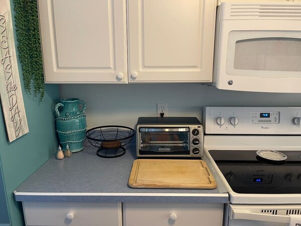 A kitchen with white cabinets, a toaster oven, a microwave, and a stove.