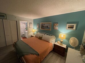 A bedroom with a bed, bedside tables, a nightstand, a fan, and a window. - Sunset & Ocean Front Views-FM-Beach(Pool is Open) (Fort Myers Beach)