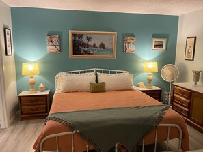 Ein Schlafzimmer mit einem Bett, zwei Nachttischen, einer Kommode und Wandbildern.