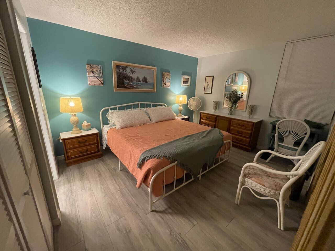 A bedroom with a bed, bedside tables, a chair, and wall art.