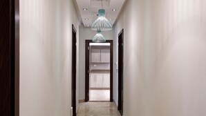 A hallway with a marble floor, white walls, and three pendant lights. - VESTA - Luxury Roof APT - 2BR - New Cairo (IV) (New Cairo City)
