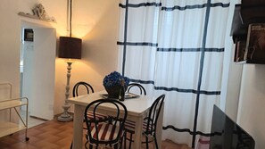 A dining area with a table for two, featuring a decorative basket and a bottle of wine.