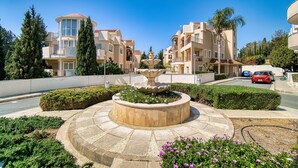 Un quartier résidentiel doté d’une fontaine centrale, entouré de jardins bien entretenus et de différents types de bâtiments.