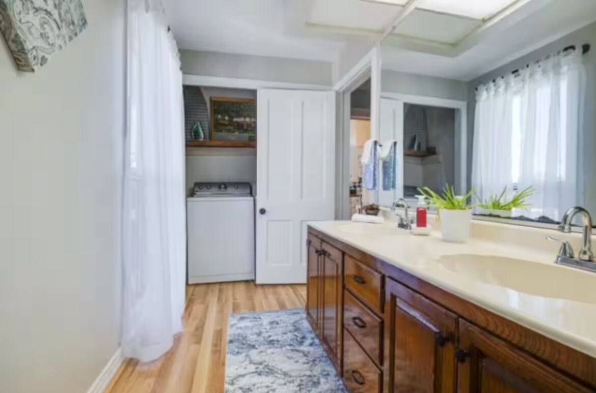 Une cuisine compacte dotée d’une cuisinière intégrée, d’un grand miroir et d’un évier.