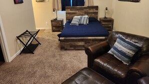 A bedroom with a wooden bed, a leather couch, a small side table, and a nightstand. - Charming studio in enchanting Colorado Springs with WiFi, AC (Colorado Springs)