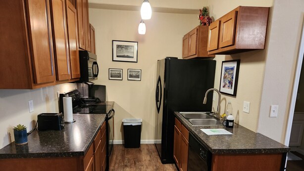 A kitchen with wooden cabinets, a black refrigerator, a sink, and a countertop. - Charming studio in enchanting Colorado Springs with WiFi, AC (Colorado Springs)