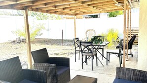 Ein Außenbereich mit einer Terrasse, Korbmöbeln und einer Holz-Pergola.