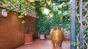 Un mur de briques agrémenté d’une treille métallique et de plantes en pot.