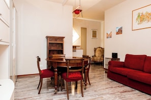 A dining area with a wooden table and chairs, a red sofa, and a chandelier.