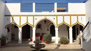 A courtyard with arches, a fountain, and potted plants.