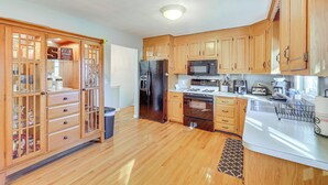 Una cocina con armarios de madera, un refrigerador de acero inoxidable, un microondas y una estufa.