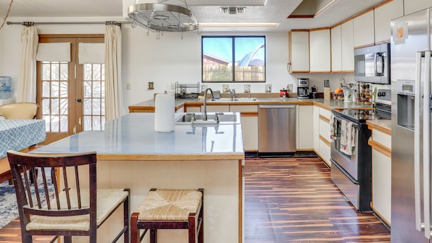 Cozinha moderna com ilha central, eletrodomésticos de aço inoxidável e uma grande janela.
