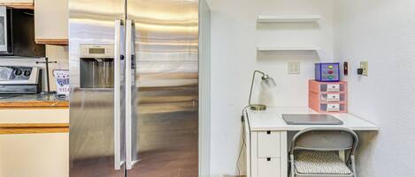 Una piccola cucina attrezzata con frigorifero in acciaio inossidabile, un forno a microonde e un piano di lavoro.