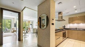 A modern kitchen with a central island, a dining area with a round table, and a living space with a sofa and a TV.