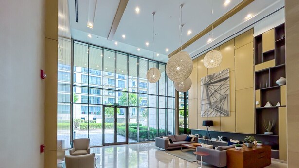 A spacious lobby with a modern design, featuring a seating area with sofas and armchairs, a coffee table, and a large abstract painting on the wall.