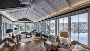 A spacious sunroom with large windows, a ceiling fan, and a cozy seating area with a fireplace.
