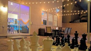 An outdoor area with a chessboard set up, a table, chairs, and string lights. - 8 BEDROOM Fun Smart Stylish Home, 8 Minutes to the Strip (Las Vegas)