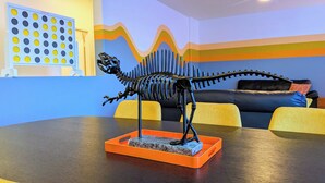 A dinosaur skeleton model on a table in a room with a blue and orange wall design. - 8 BEDROOM Fun Smart Stylish Home, 8 Minutes to the Strip (Las Vegas)