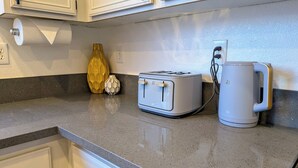A kitchen counter with a toaster, a coffee maker, and decorative vases. - 8 BEDROOM Fun Smart Stylish Home, 8 Minutes to the Strip (Las Vegas)
