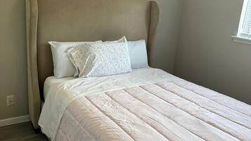 Un dormitorio con cama, cabecera y ventana.
