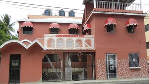 Un bâtiment à la façade rouge, doté de nombreuses fenêtres surmontées d’auvents rouges, et d’une enseigne indiquant « CONDORROYALPARK.COM ».