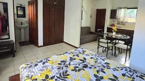 Ein Schlafzimmer mit Bett, Schreibtisch, Stuhl, Sofa, Kleiderschrank und einem Badezimmer.