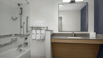 A modern bathroom with a bathtub, shower, vanity, and a large mirror.