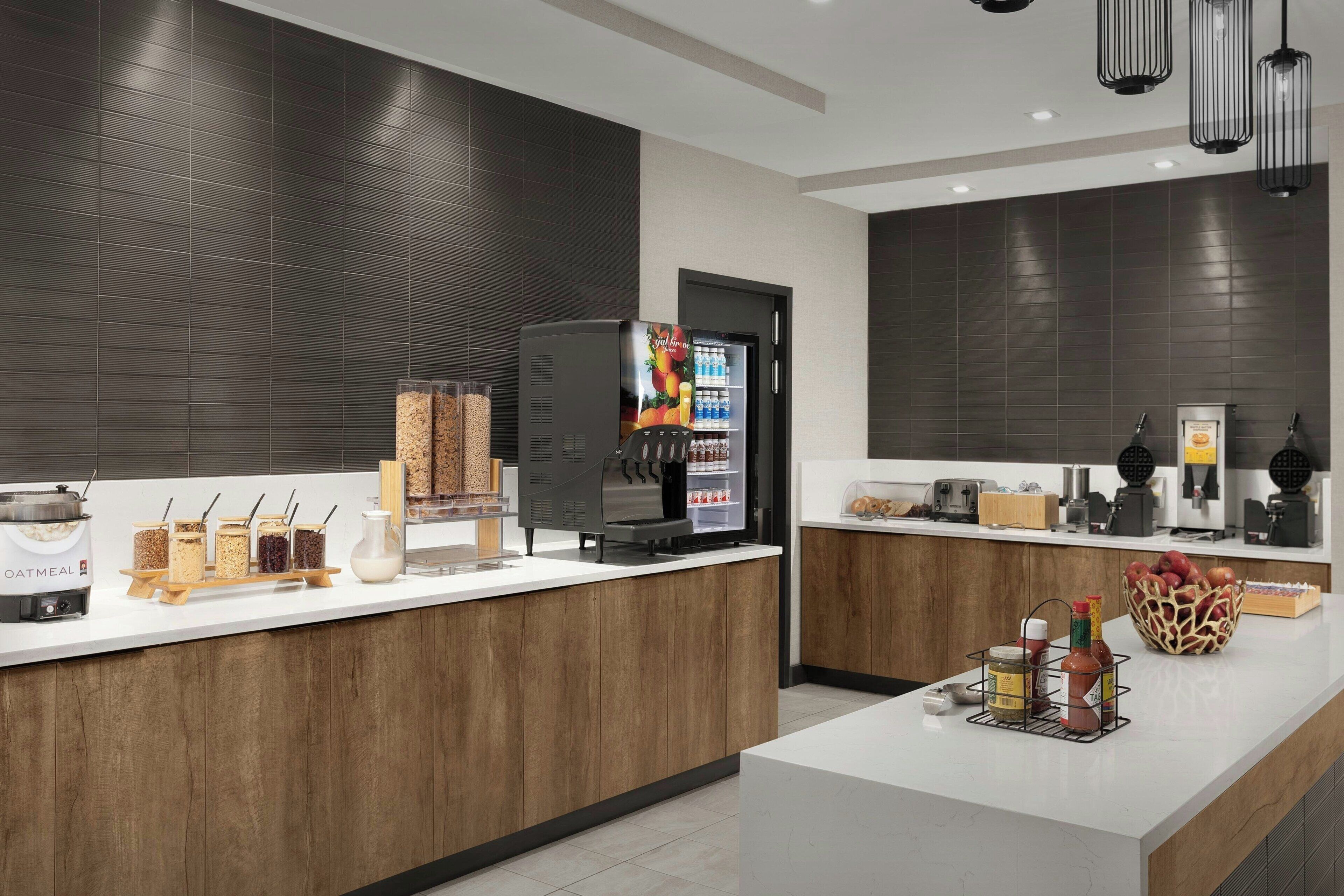 Een moderne keuken met een koffieapparaat, een koelkast en diverse etenswaren op het aanrecht.