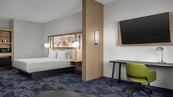 Een hotelkamer met een bed, bureau, stoel en een flatscreen televisie.