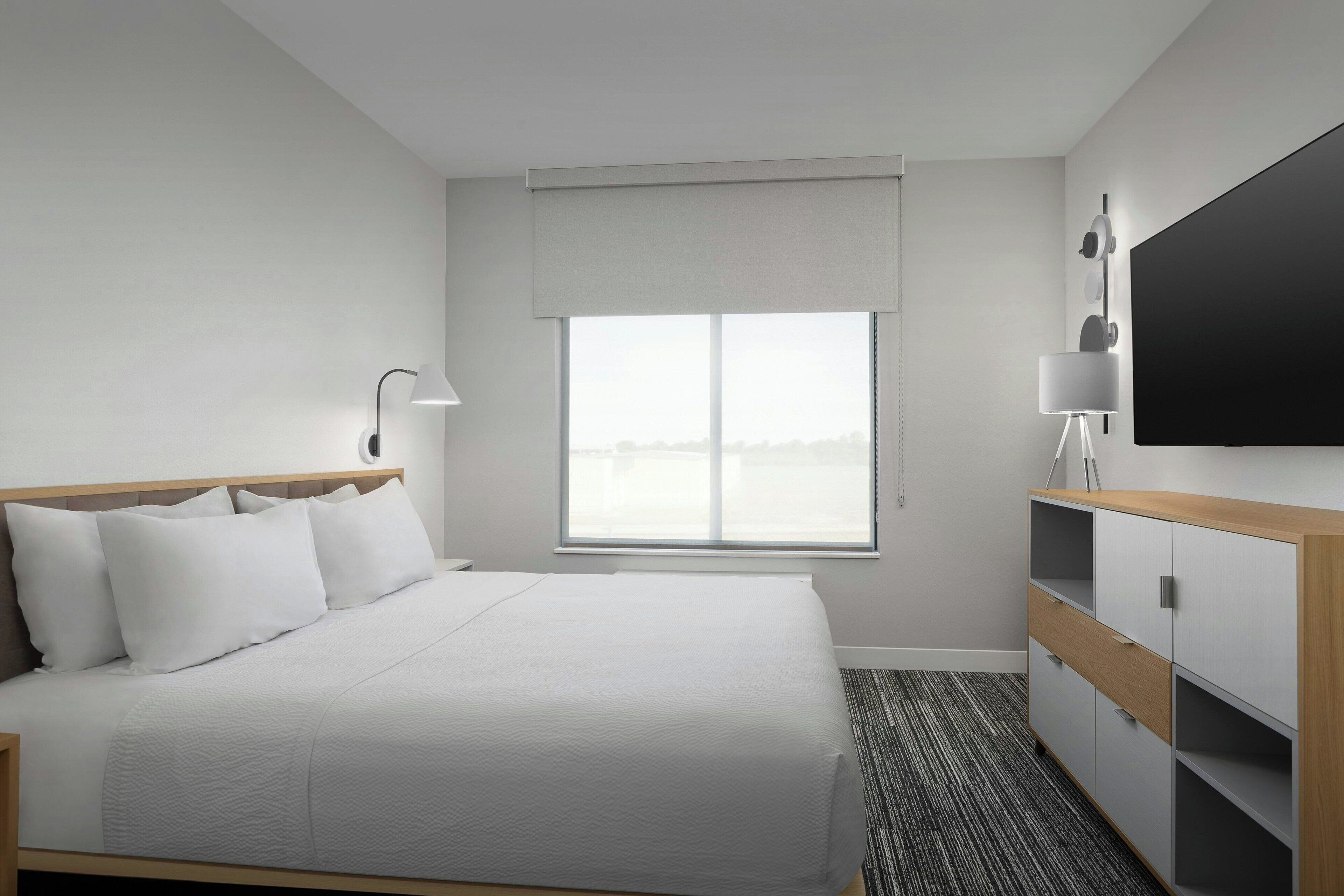Una habitación de hotel con una cama, un escritorio, una silla, un televisor y una ventana.