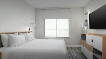 Una habitación de hotel con una cama, un escritorio, una silla, un televisor y una ventana.