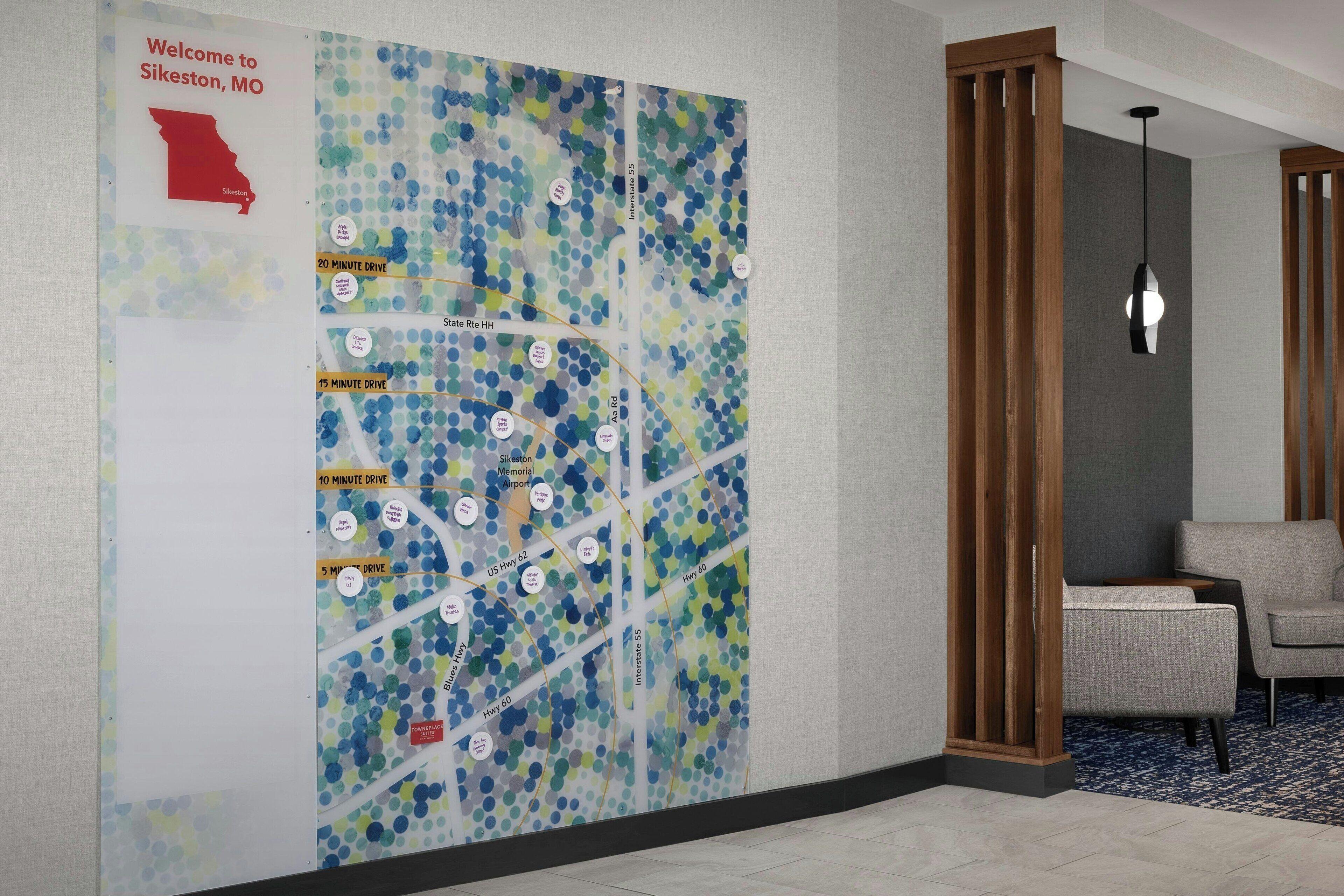 A hotel lobby with a large wall map, a reception desk, and seating area.