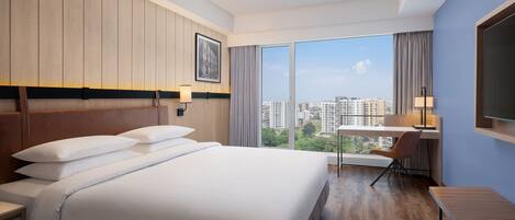A hotel room with a large bed, a desk, a chair, and a TV.