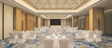 A conference room with round tables, white chairs, and a patterned carpet.